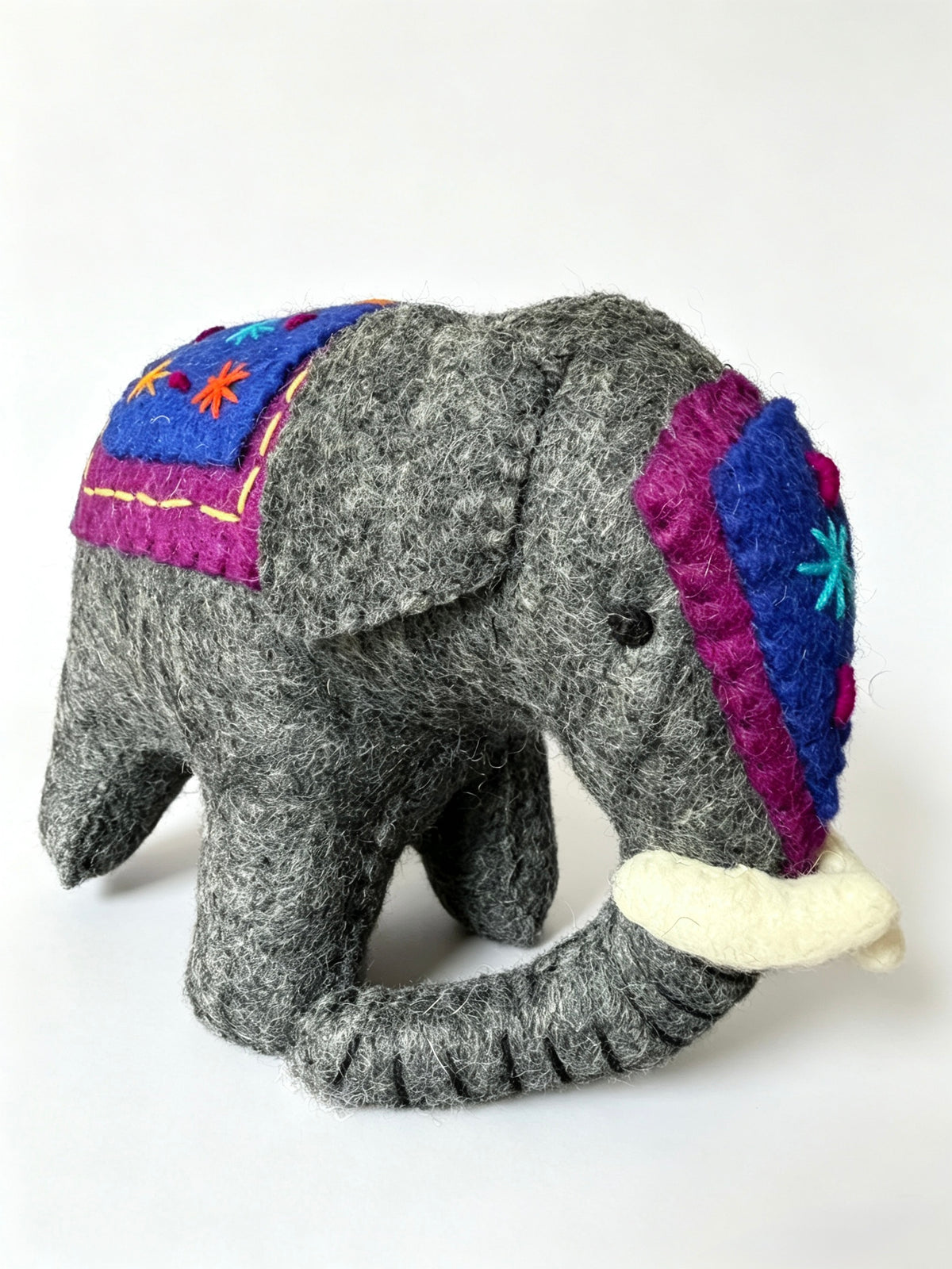 Close view of handmade wool felt elephant figurine with embroidered blanket