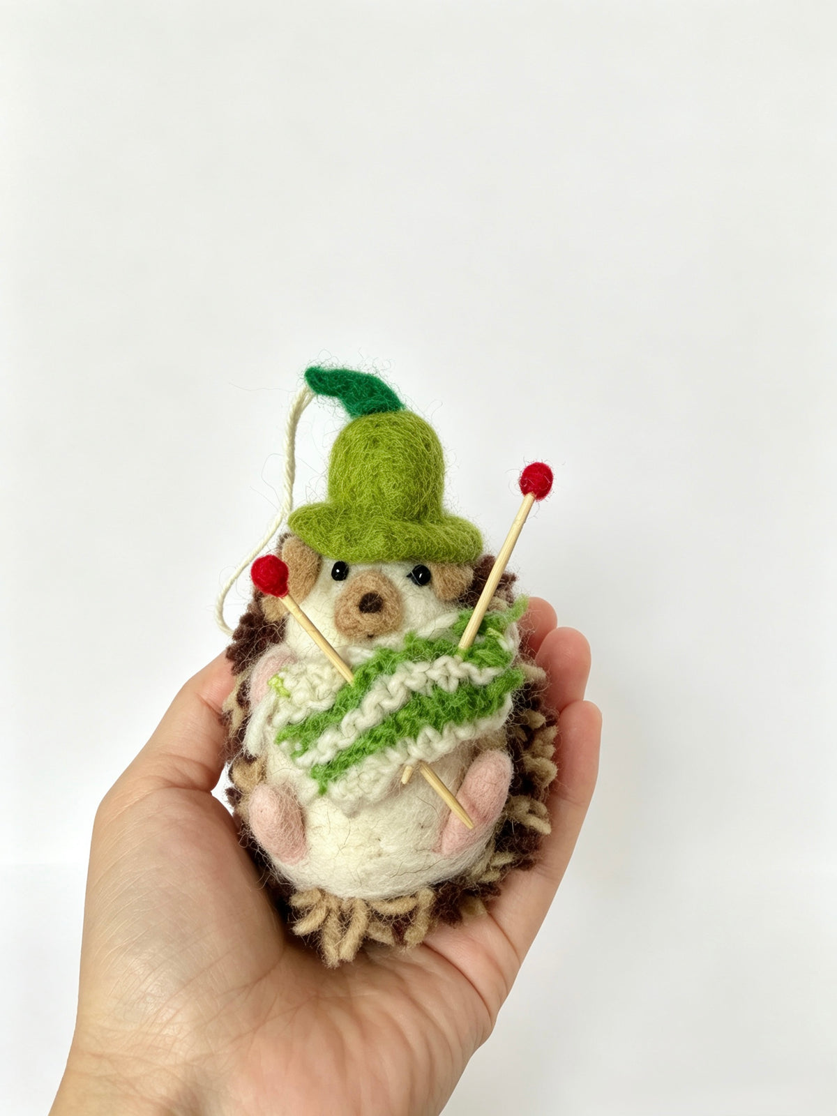 Handmade wool felt knitting hedgehog ornament held in a hand