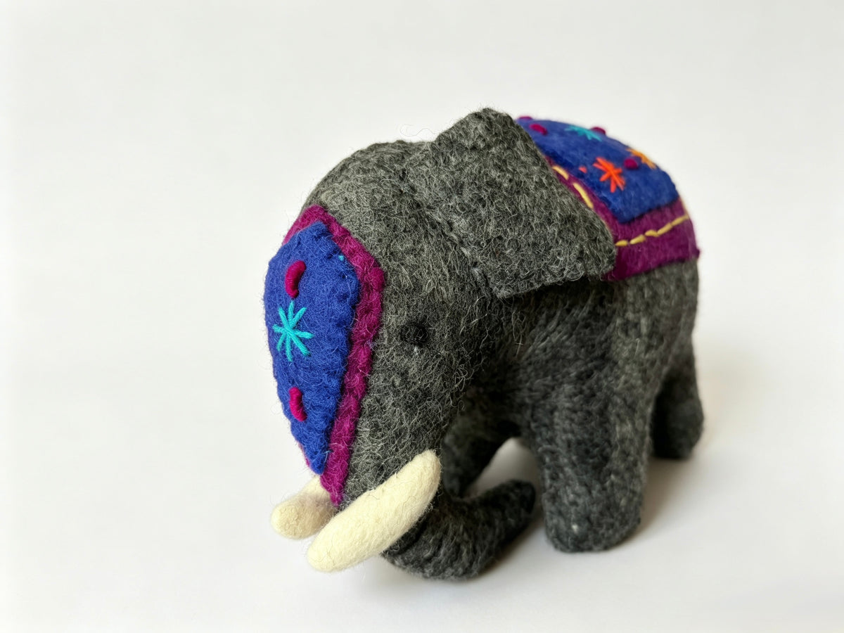 Three quarter view of handmade wool felt elephant with colourful embroidered head covering