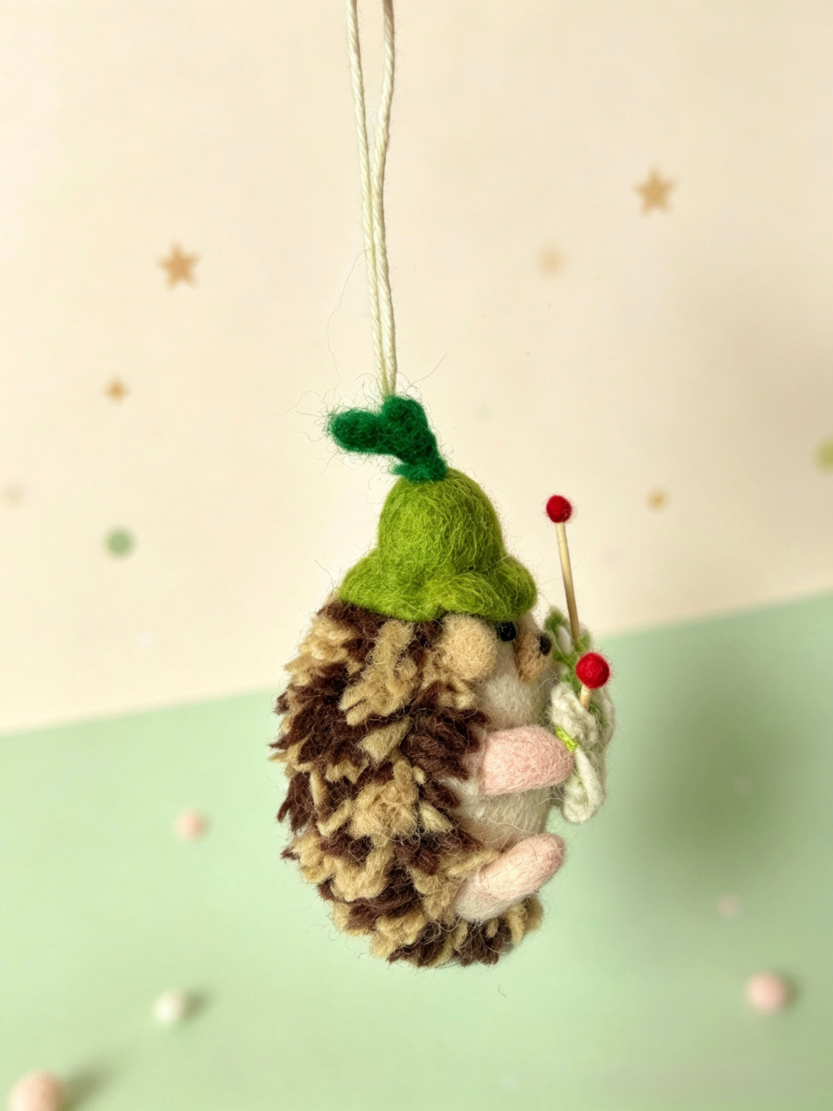 Handmade wool felt hedgehog knitting ornament in a soft green setting