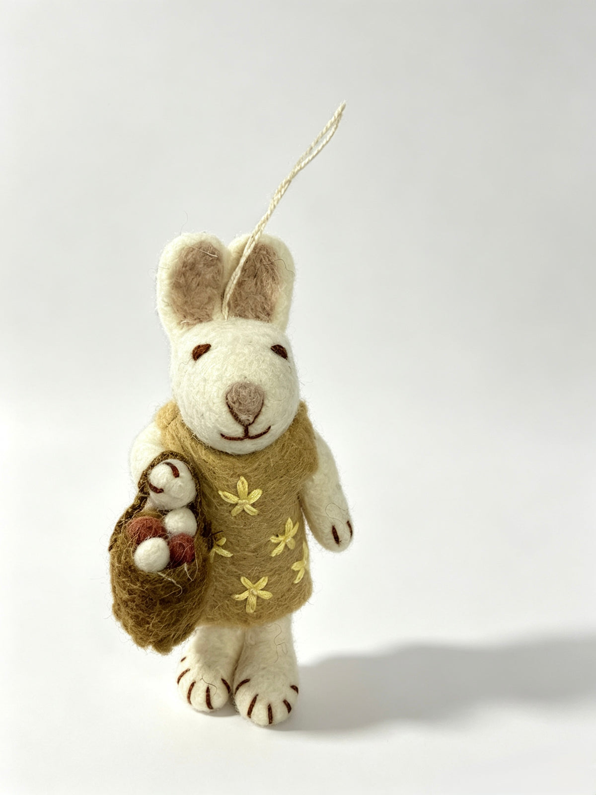 Handmade wool felt bunny rabbit ornament in a garden with flowers