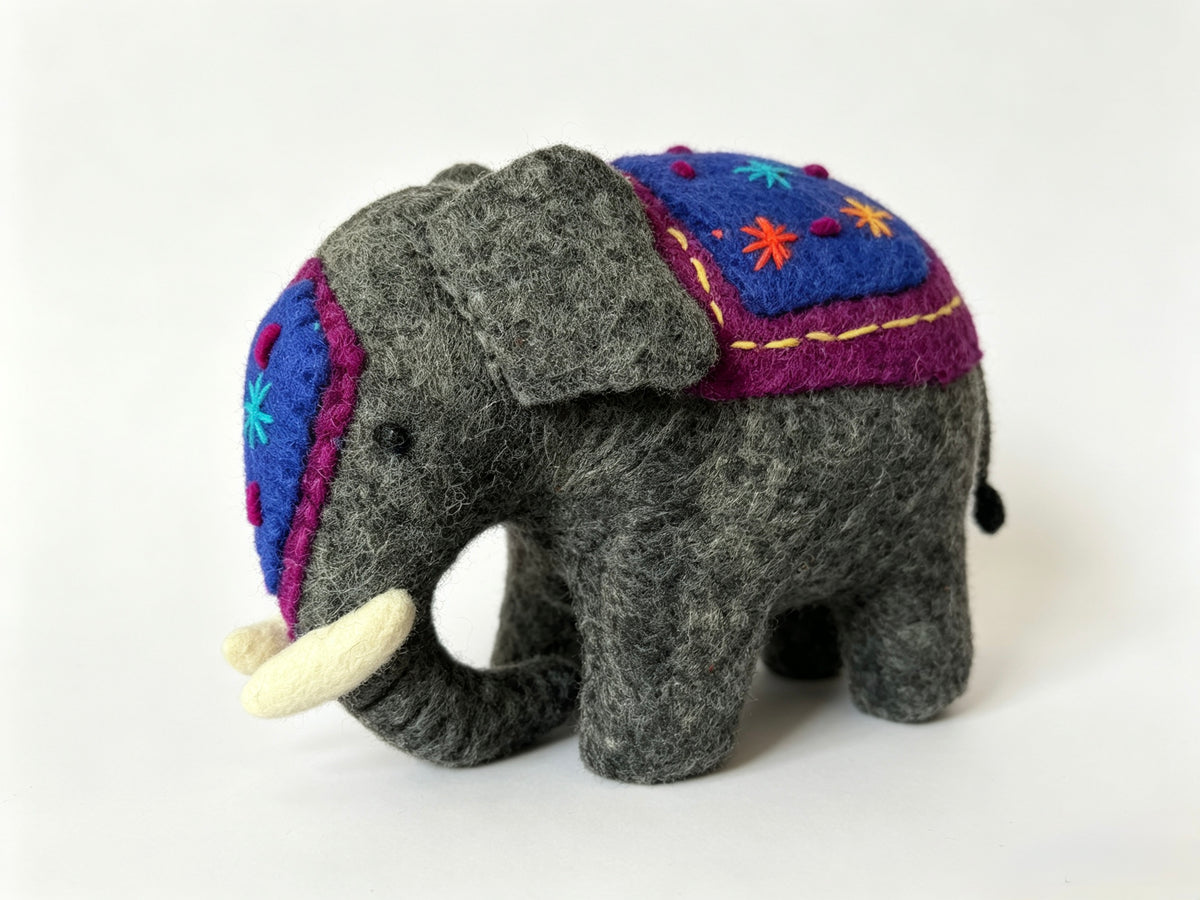Side view of handmade wool felt elephant ornament on a white background