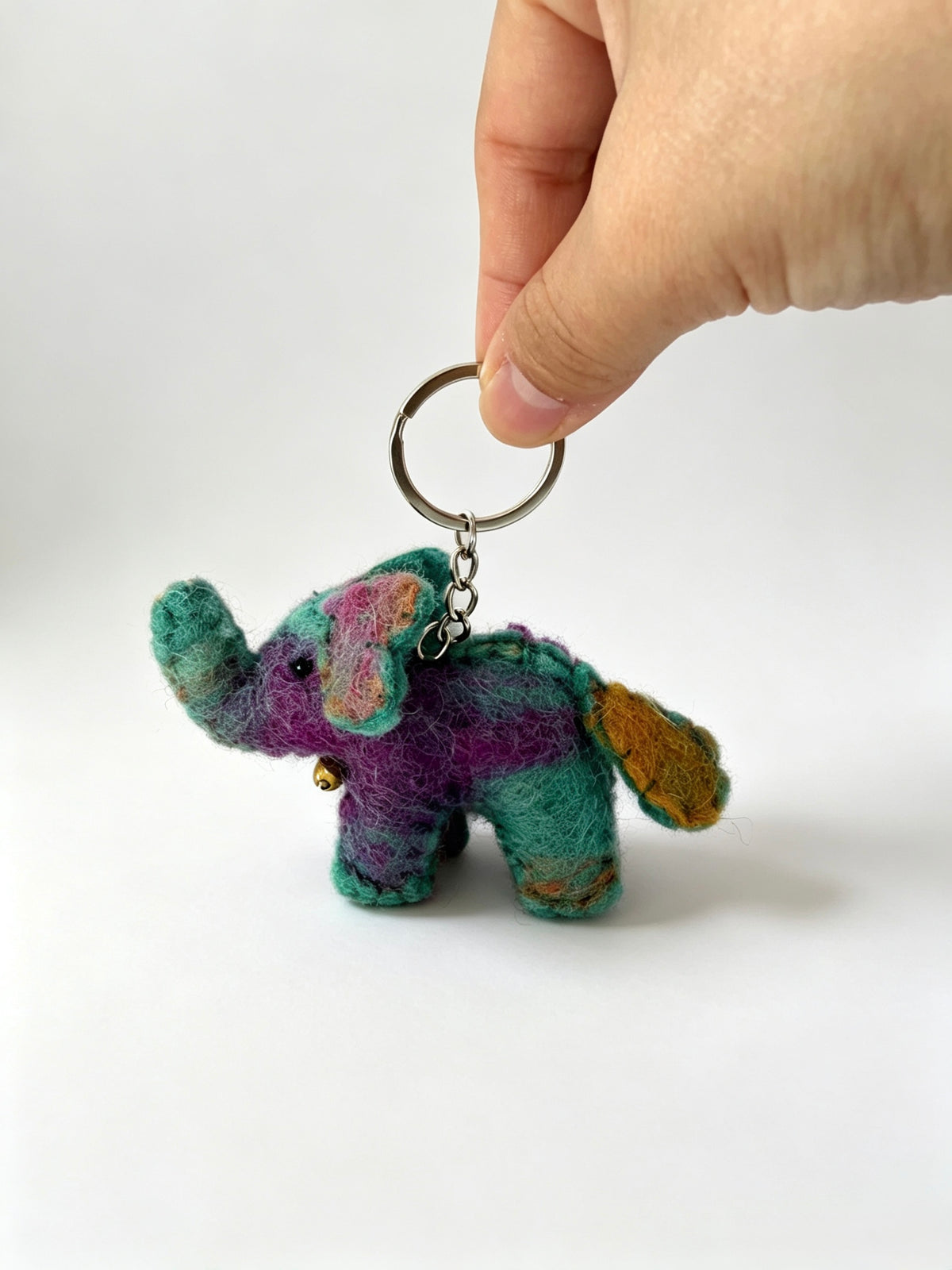 Handmade felt elephant keychain photographed outdoors in a meadow