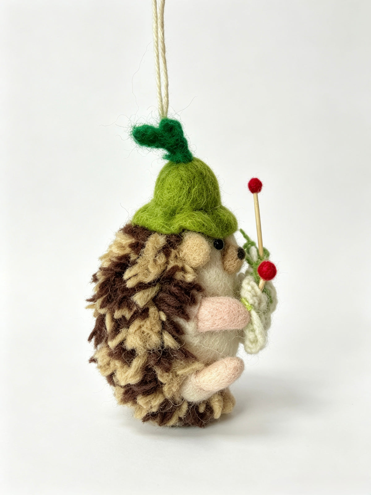 Profile of handmade wool felt hedgehog ornament wearing a green apple hat