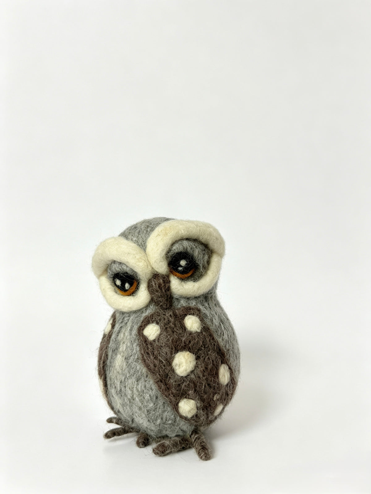 Handmade grey wool felt owl figurine photographed on a white background