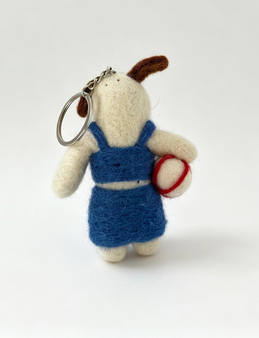 Handmade wool felt dog keyring wearing a blue beach outfit and holding a volleyball