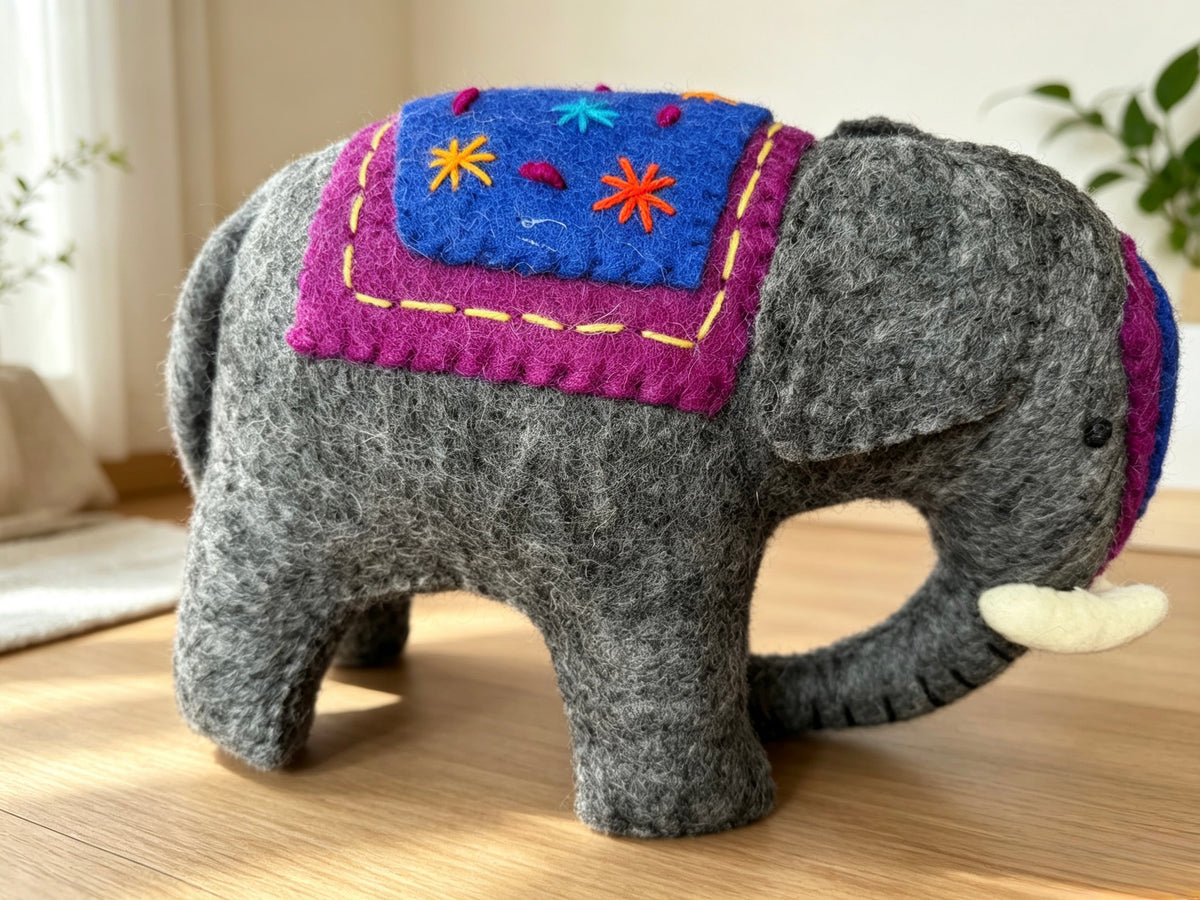 Handmade grey wool felt elephant ornament displayed on a wooden table